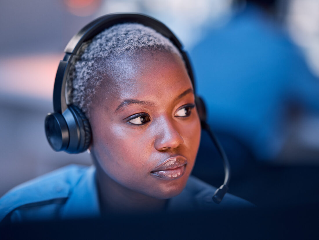 Serious looking phone operator looks at computer screen while answering a call