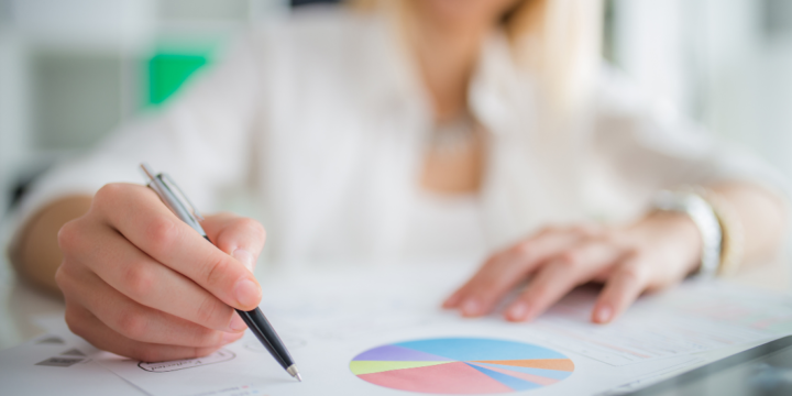 Close up of a woman's hand marking a printed pie chart with a pen.